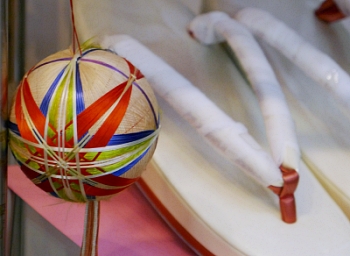 Temari multicolore esposta in vetrina a fianco a zori 