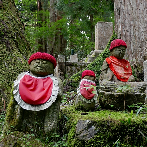 tre statute di jizo in meditazione con berretto e bavaglino rossi