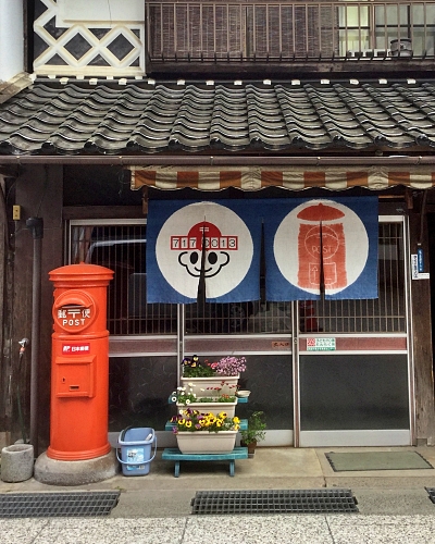 Buca della posta cilindrica rossa e noren con codice postale e buca delle lettere disegnati