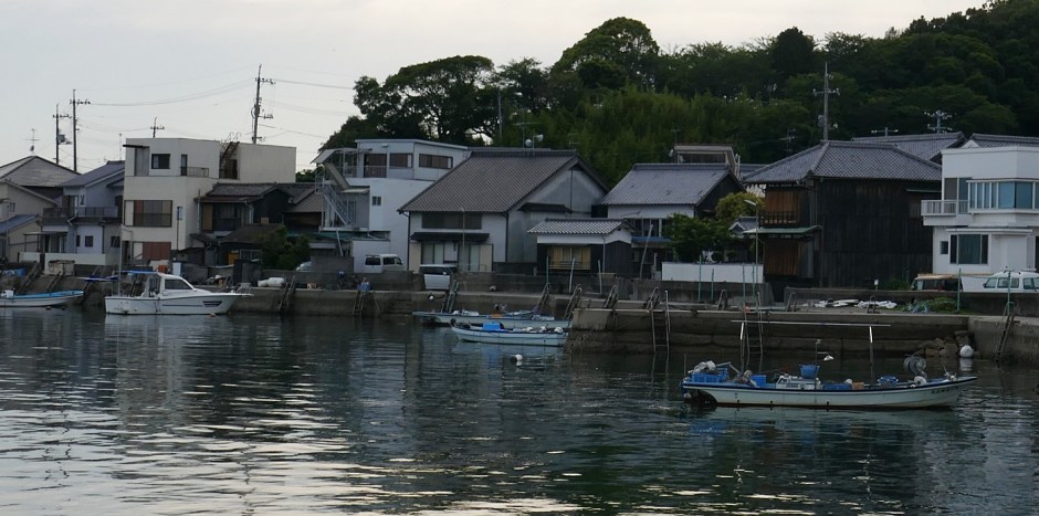 Costa con case e barche sul mare di sera