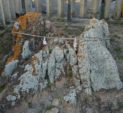 Scoglio sacro coperto di licheni e cinto da una corda votiva.